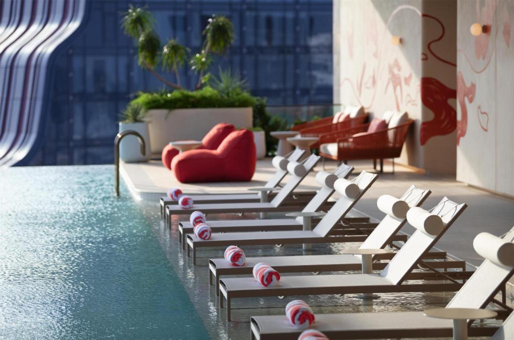 Poolside loungers placed directly along the water beside a muralled terrace.