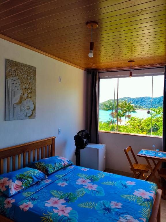 a bedroom with a bed and a large window at Mar Doce Lar Suítes Trindade in Trindade