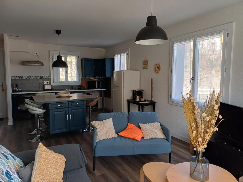 a living room with a blue couch and a kitchen at Gîte l'Ermitage in Cahors