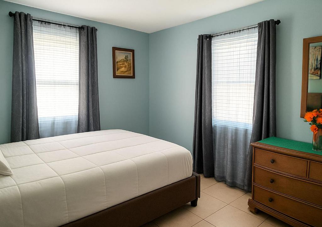 een slaapkamer met een bed, 2 ramen en een dressoir bij Perfect Beach Gateway in West Palm Beach