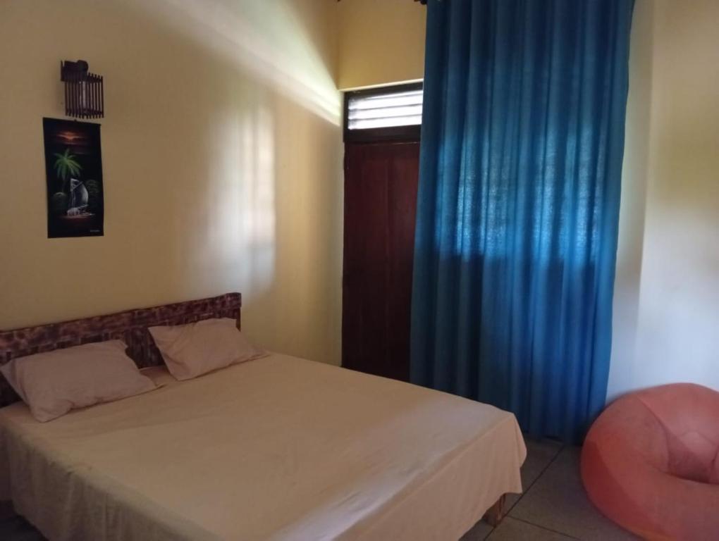 a bedroom with a bed and a blue curtain at Samee Villa & Hostel Airport in Seeduwa