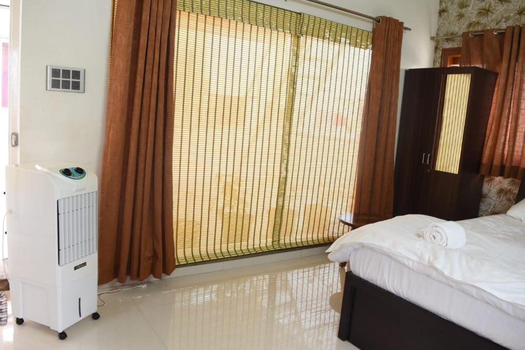 een slaapkamer met een bed en een groot raam bij Aakruthi Homestay in Davangere