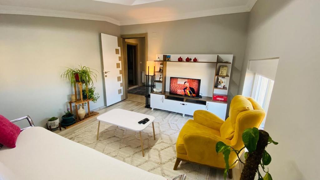 een woonkamer met een gele stoel en een tv bij Peribacası Manzaralı Modern Daire 2 in Urgup
