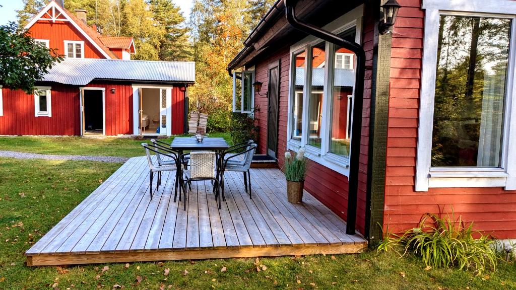 a wooden deck with a table and chairs on a house at Host Harmony 6 PP Cabin Close to lake in Vittsjö