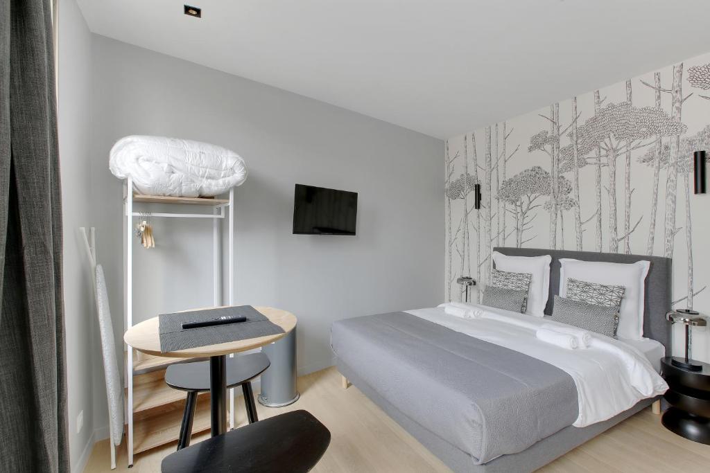 een slaapkamer met een bed, een tafel en een stoel bij Refined air-conditioned studio in Neuilly in Neuilly-sur-Seine