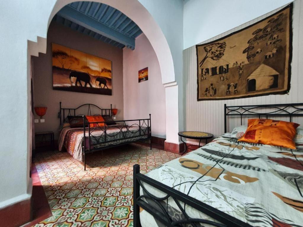 una camera da letto con due letti e un dipinto sul muro di Appartement Riad Sidi Magdoul a Essaouira