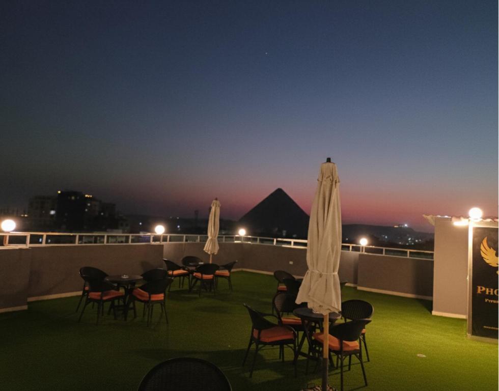 a group of tables and chairs on a balcony at night at Phoenix Pyramids View Inn in Cairo