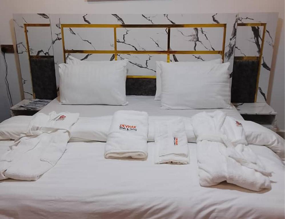 een bed met witte lakens en handdoeken erop bij DEVHAK Hotel and Suites in Warri