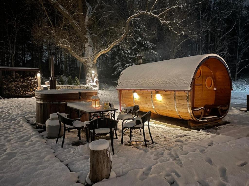 een houten hut met een tafel en stoelen in de sneeuw bij Jurajka in Żarki