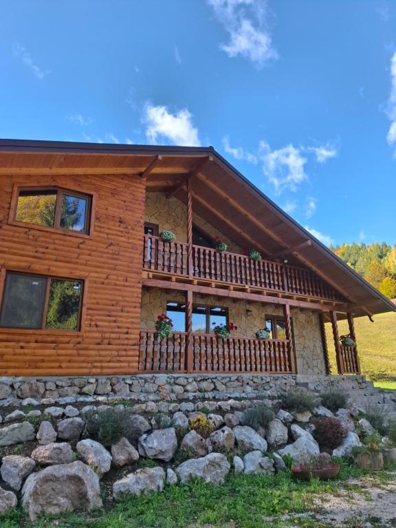 a log house with a stone wall in front of it at Cabana Luciana in Dămuc