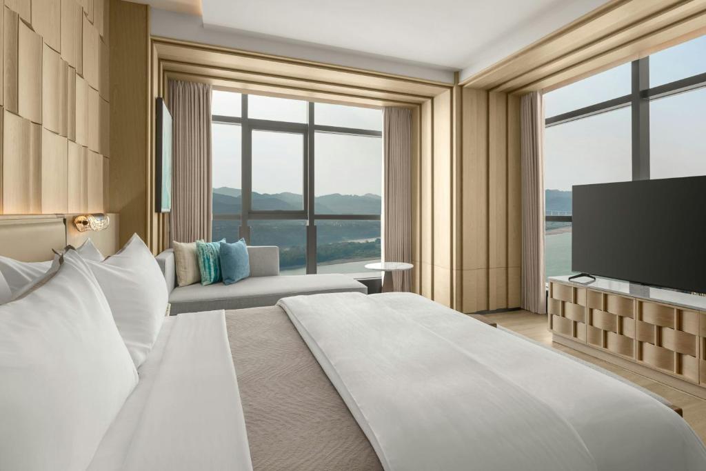 a hotel room with a large bed and a television at The Westin Yichang in Yichang