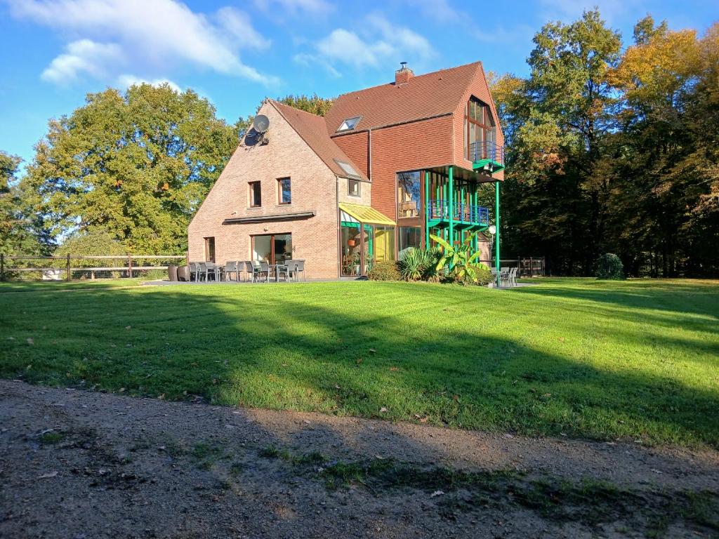 een groot bakstenen huis op een grasveld bij Gite des étangs de Saint Bale in Vrigne-aux-Bois