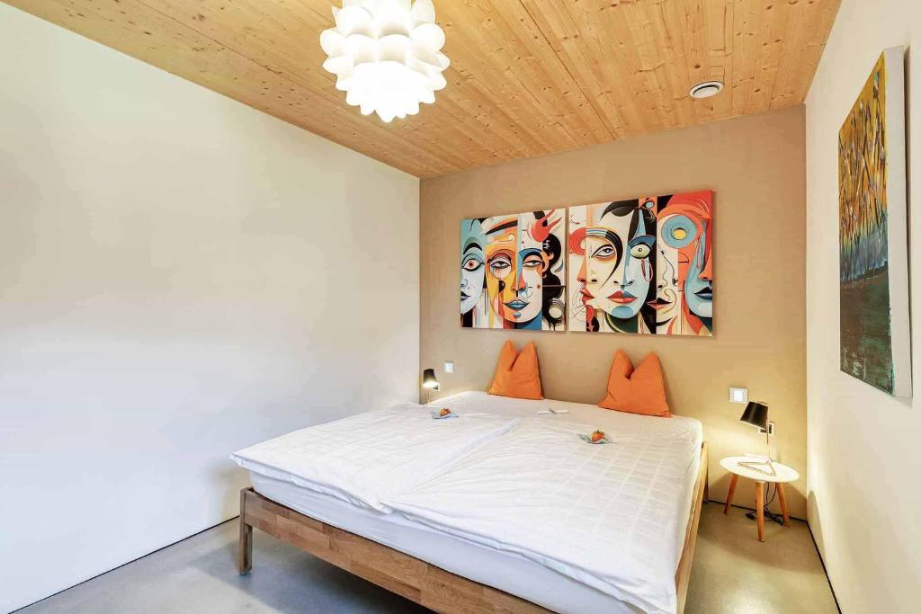 ein Schlafzimmer mit einem Bett und einem Gemälde an der Wand in der Unterkunft LIEBLINGSECK nachhaltige 5-Sterne Ferienwohnung - Direkt am Chiemsee in Gstadt am Chiemsee