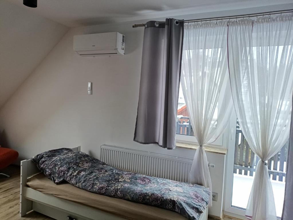 een slaapkamer met een bed en een groot raam bij Apartament Przylesie in Stężyca