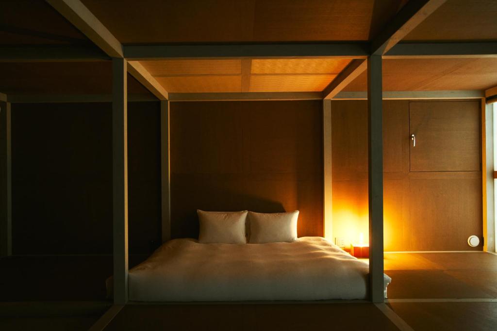 een bed met witte lakens en kussens in een kamer bij A&A Okayama in Okayama