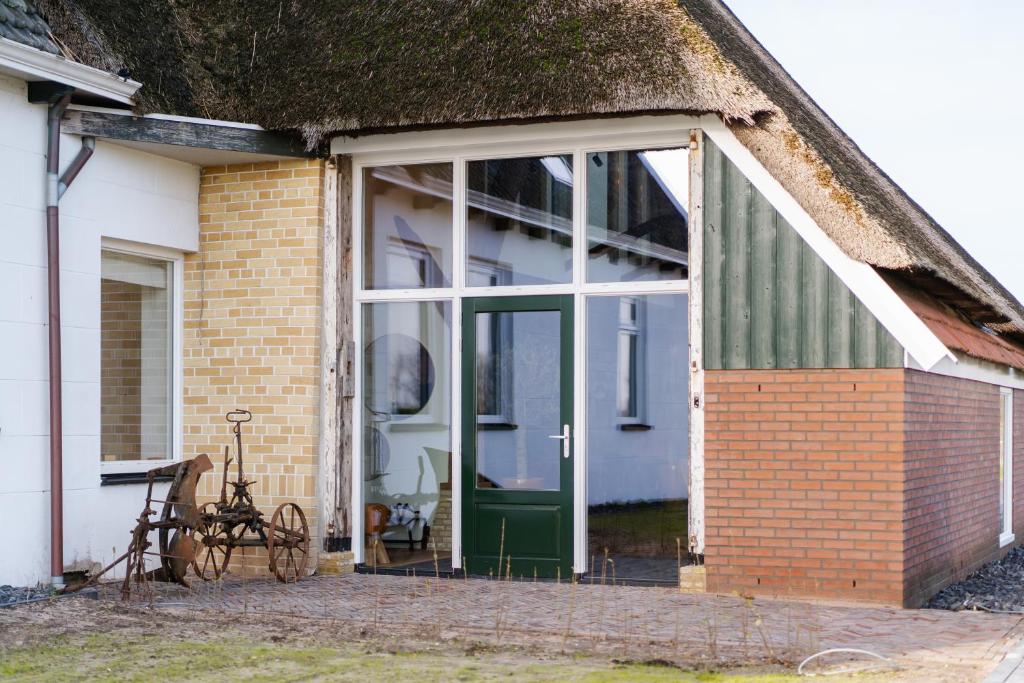een huis met een grote glazen deur en een fiets ervoor bij B&B Lindehoeve Texel in Den Hoorn