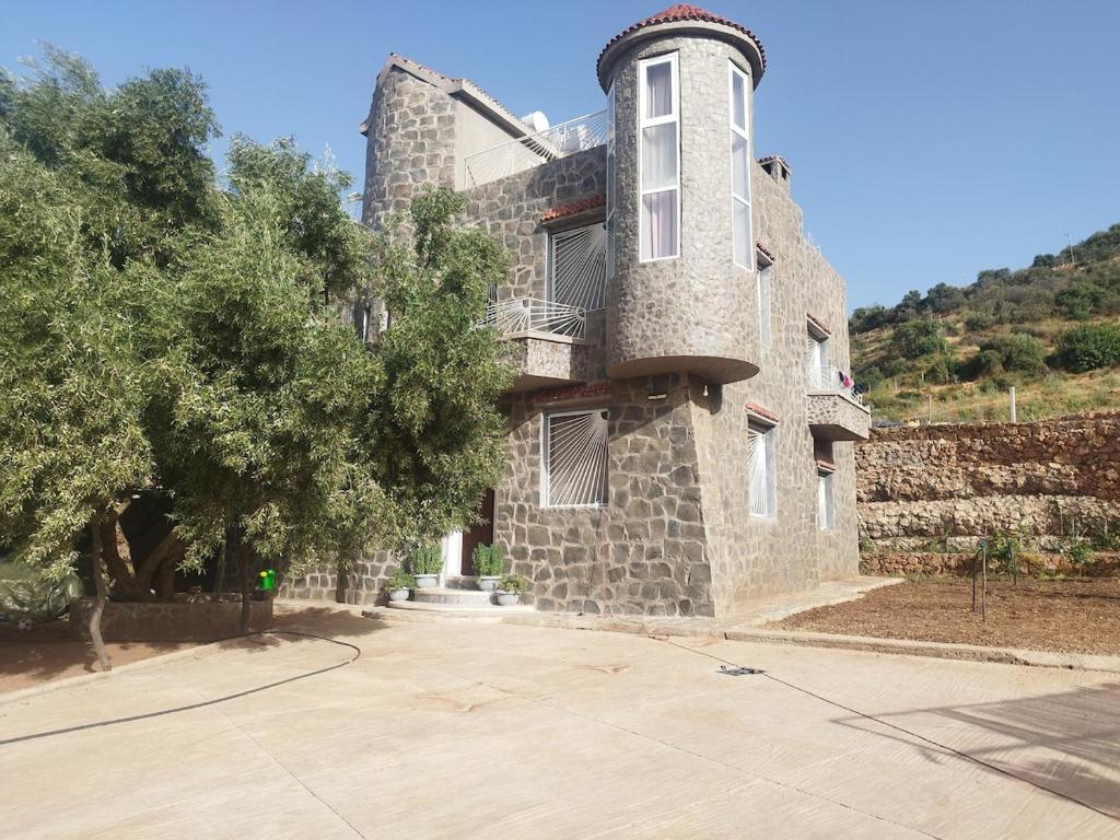 a large stone building with a tree in front of it at Luxurious mountain villa avec wifi in El Ksiba