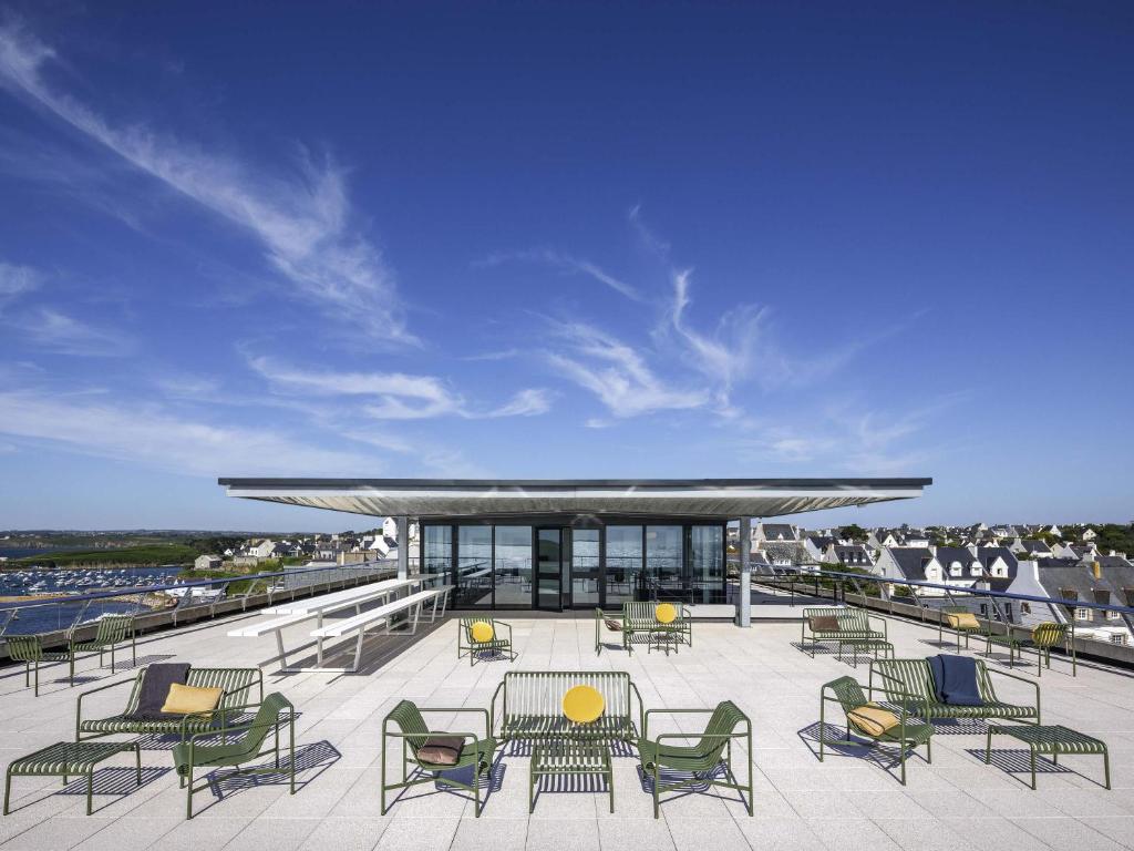 een patio met stoelen en tafels en een gebouw bij Sainte-Barbe Hotel & Spa Le Conquet - MGallery Collection in Le Conquet