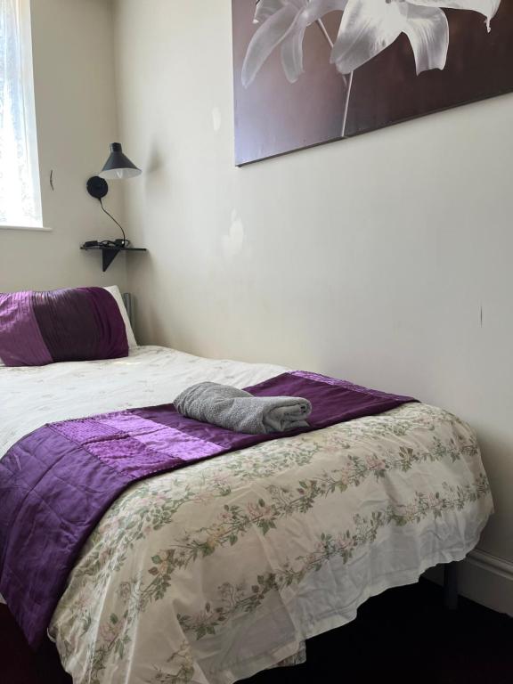 a bedroom with a bed with a purple blanket at Love & Peace in Orpington