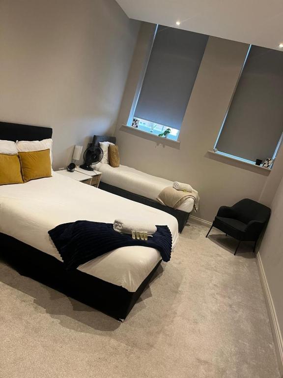 two beds in a room with two windows at Prime Leeds- Spacious Cinema apartment in Central Station