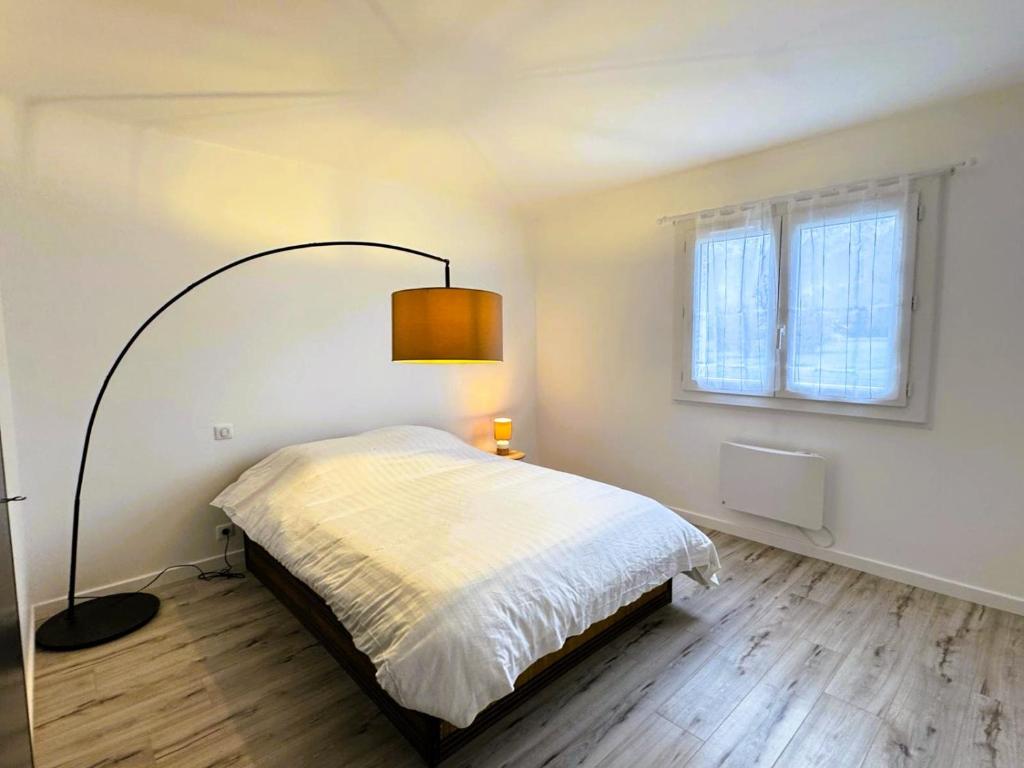een witte slaapkamer met een bed en een lamp bij Maison partagée Bonneville in Bonneville