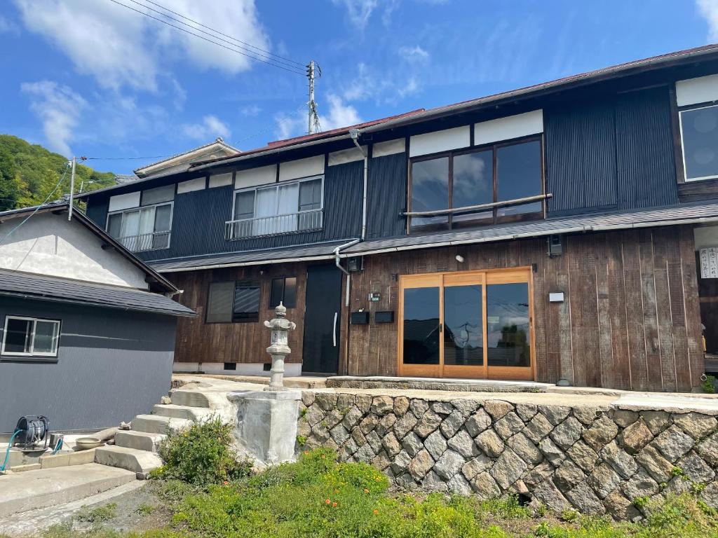 a large black house with a stone wall at イヤシロチomoya in Onomichi
