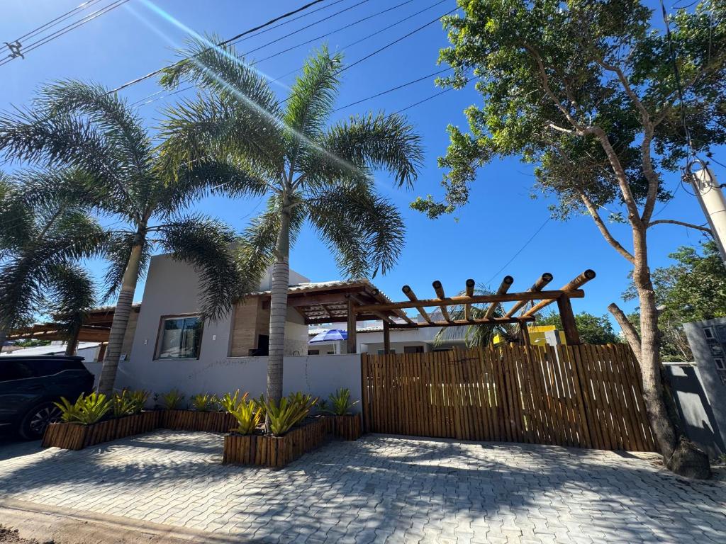 a house with palm trees in front of a fence at Residencial Rocha - Praia de Guaratiba - Prado - Ba in Prado