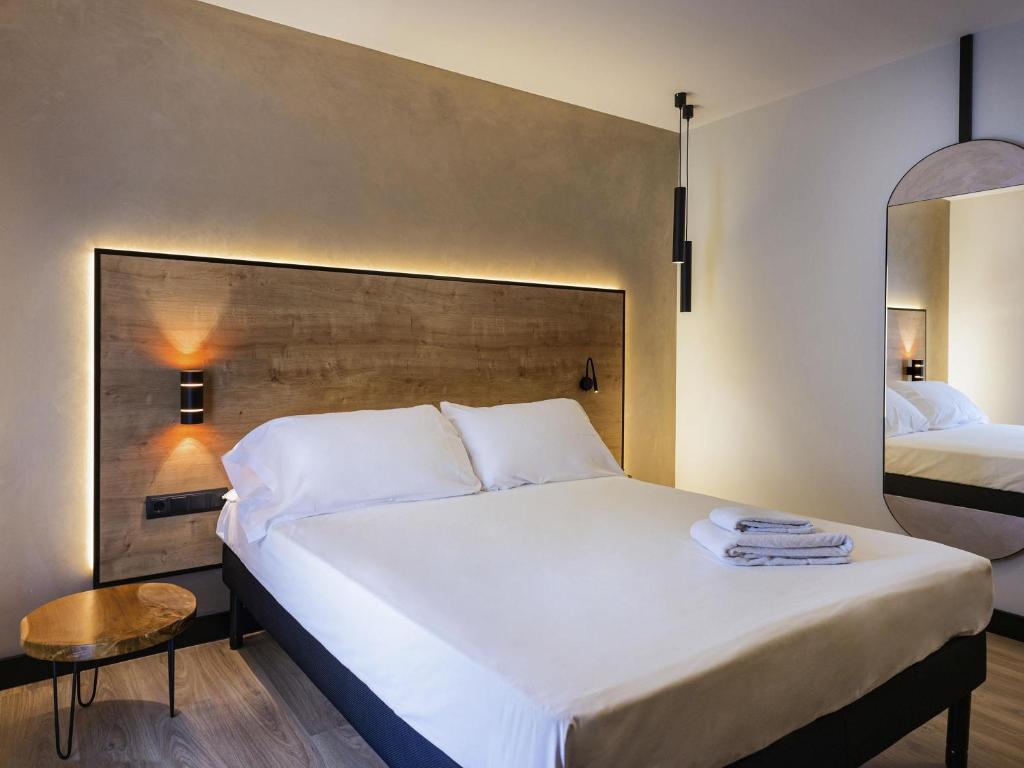 a bedroom with a large white bed and a mirror at Ibis Styles Figueres Ronda in Figueres