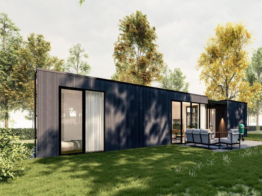 a small black house on a grassy field at Sustainable Stay by Palette Resort de-Steppe in Ulicoten