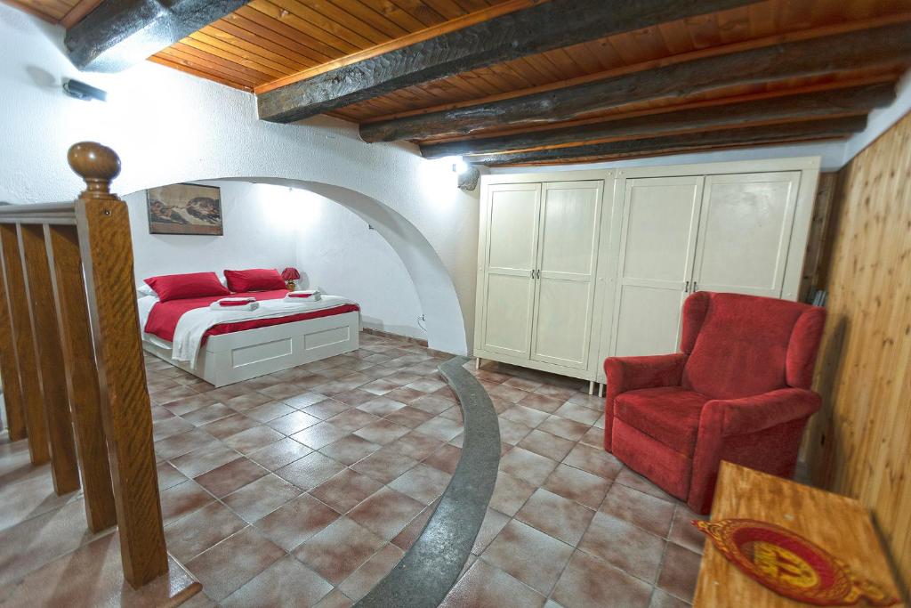 a bedroom with a bed and a red chair at Al Rifugio Nel Borgo in Vitorchiano