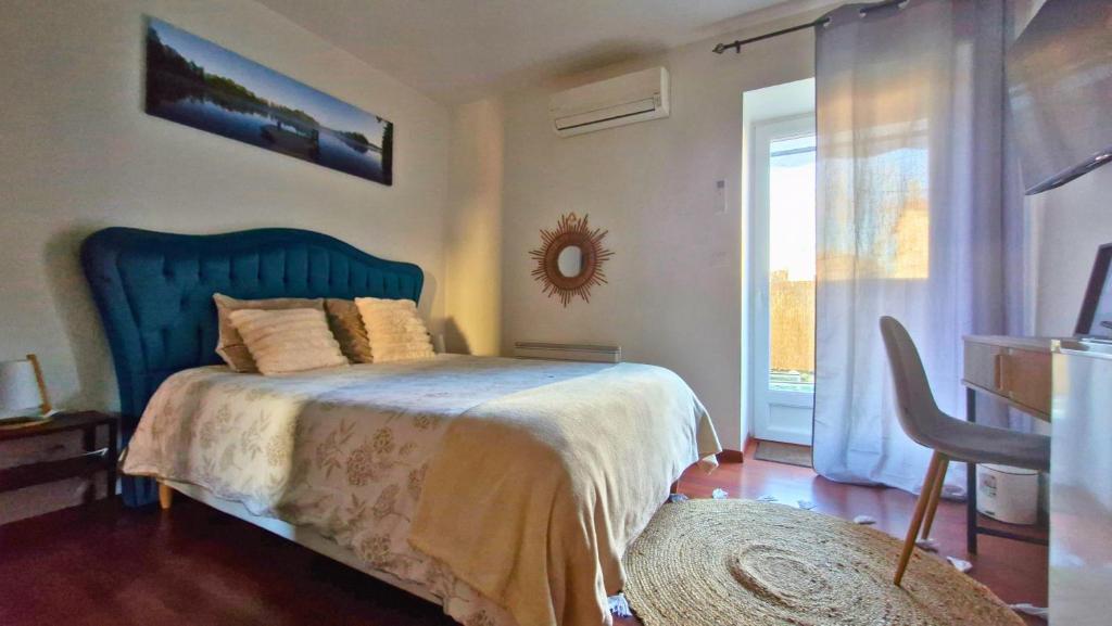 a bedroom with a bed with a blue headboard and a window at Chambre Chez l'habitant "Maïssi" in Sablons