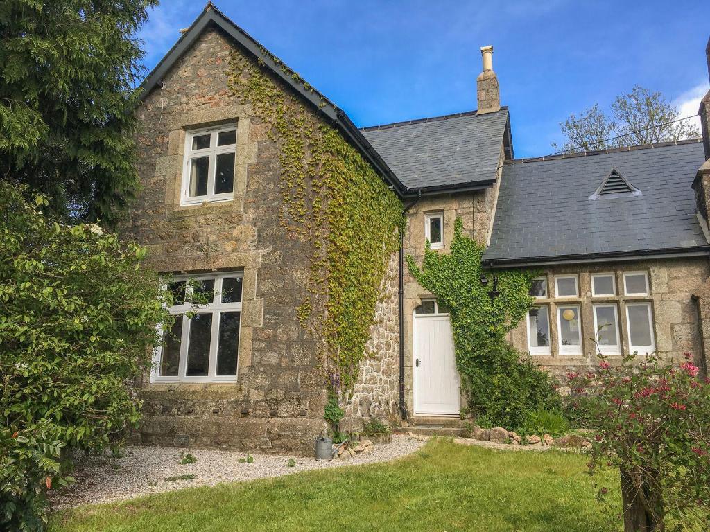 an ivy covered house with a white door at School House in Ivybridge