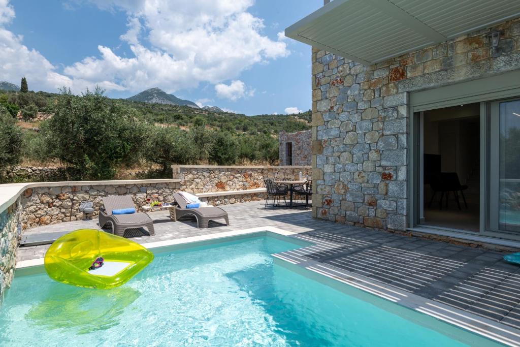a swimming pool with a yellow chair next to a house at Pasithea Villas in Neokhórion