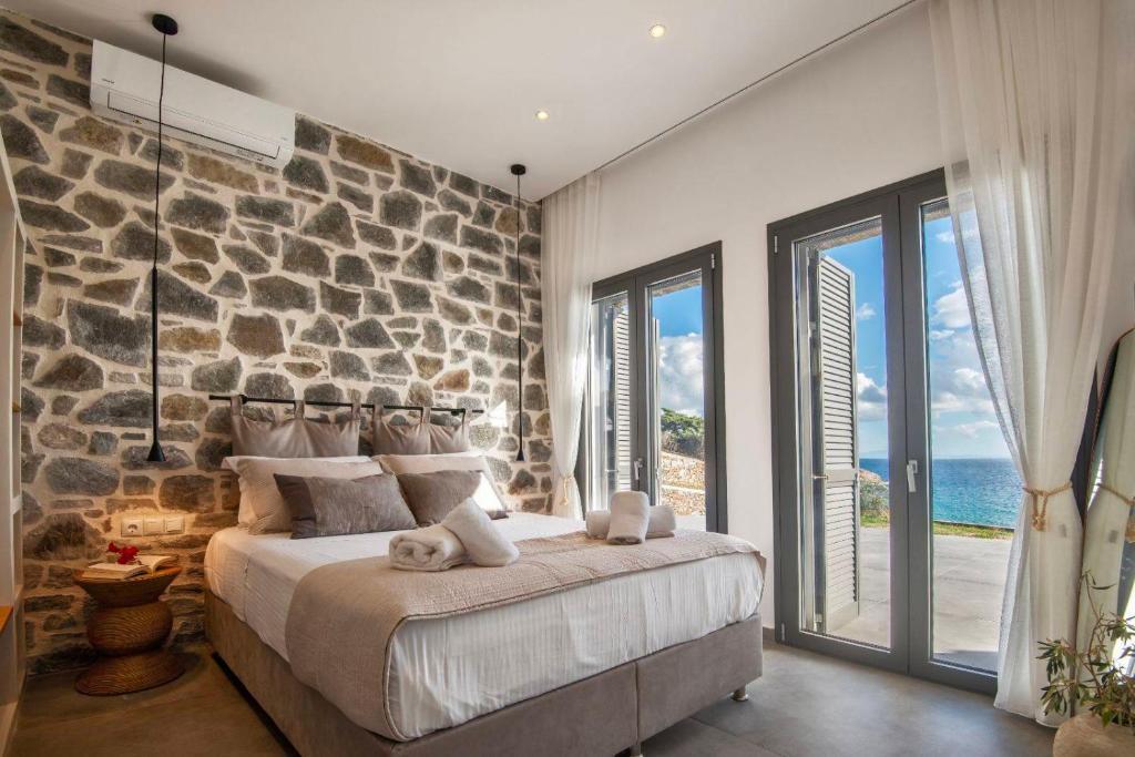 a bedroom with a large bed with a stone wall at KYAN Syros in Liaropá