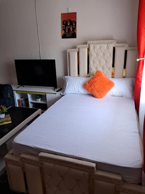 a bedroom with a bed with an orange pillow on it at Watene's Homes in Nairobi