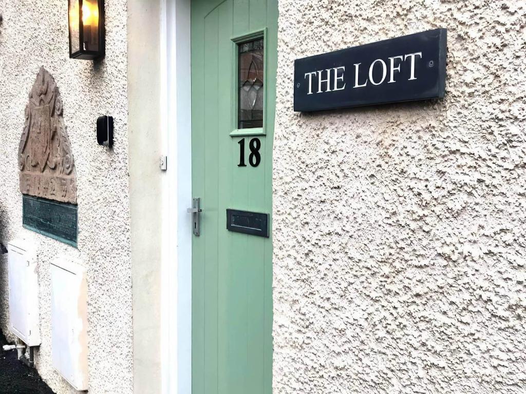 een gebouw met een groene deur en een bord erop bij The Loft in Anstruther