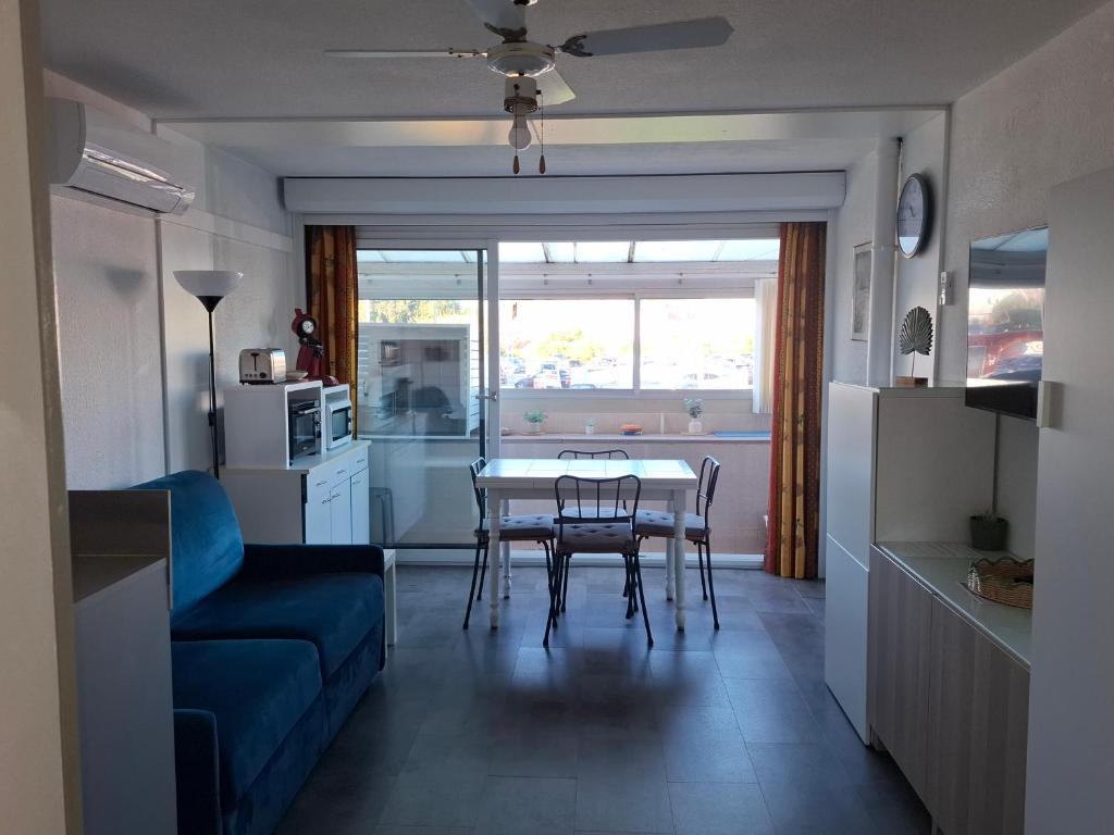 un salon avec un canapé bleu, une table et des chaises dans l'établissement YUCCA, au Lavandou