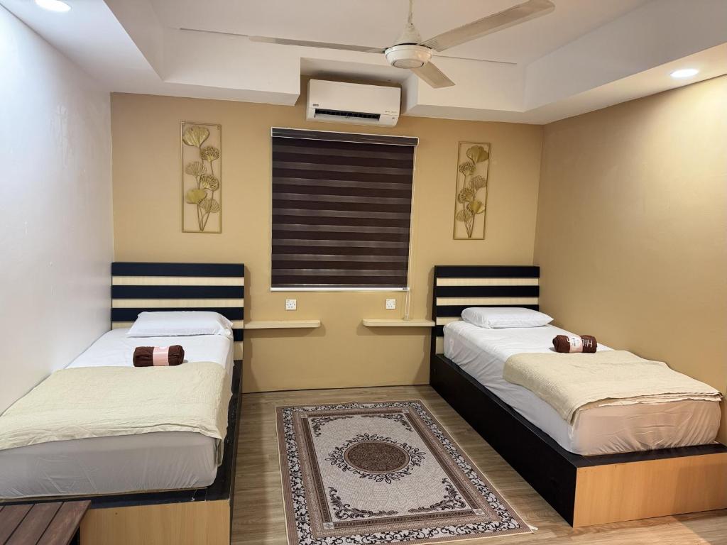 two beds in a room with a window and a rug at Zetta Roomstay in Kuala Lumpur