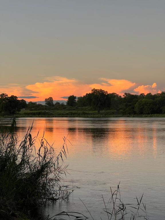 een waterlichaam met een zonsondergang op de achtergrond bij Edsam Lodge in Divundu