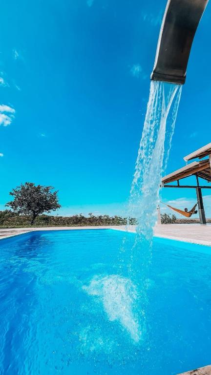 a dolphin is under a fountain in a pool at Chalé M in Serra do Cipo