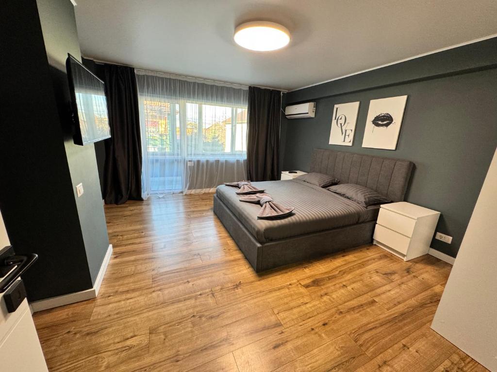 een slaapkamer met een bed en een houten vloer bij V apartament - ultra central Otopeni in Otopeni