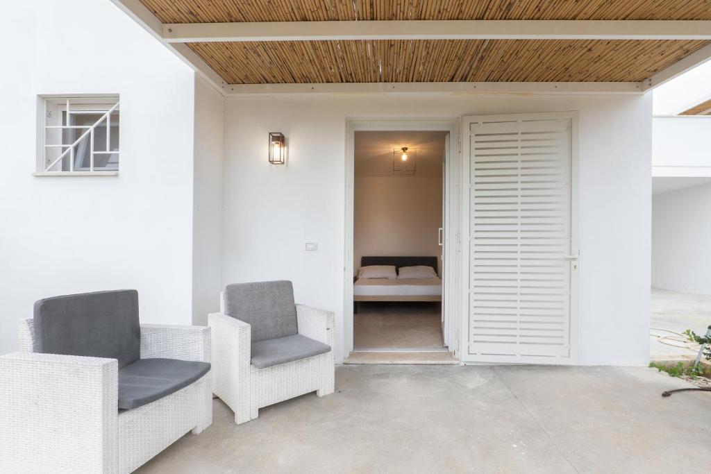 a patio with two chairs and a door to a bathroom at Masseria l'Ulìa in Gallipoli