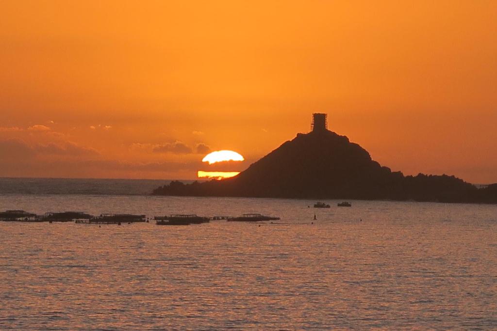 a sunset over a small island with a lighthouse on it at STUDIO LES CALANQUES in Ajaccio