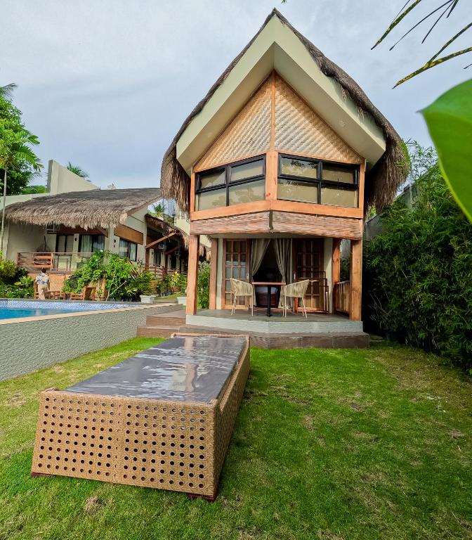 a house with a thatched roof and a pool at The Cliffhouse Samboan in Samboan
