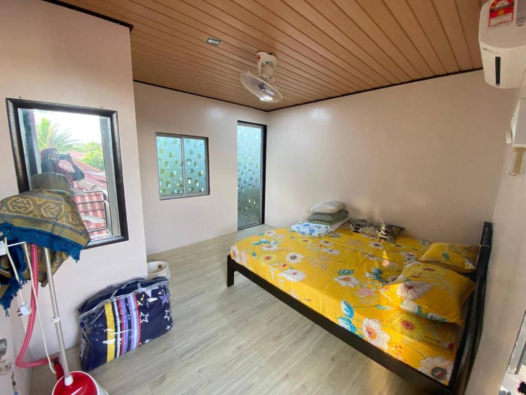 a bedroom with a bed with a yellow comforter at Umishah Cabin Jitra in Jitra