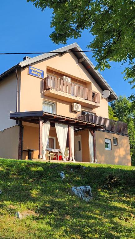 a large building with a balcony and a house at Apartments Žugec in Seliste Dreznicko