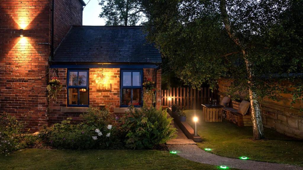 a small brick house with a garden at night at River Cottage at Old Post Office in Bardon Mill