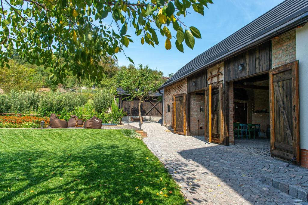a garden with a building with large sliding doors at Pensiune Old Barn House in Vàrhegy