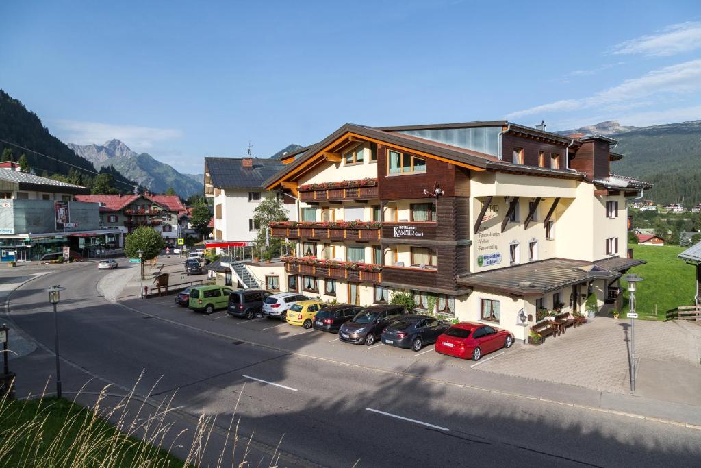 ein großes Gebäude mit auf einem Parkplatz abgestellten Autos in der Unterkunft Hotel Kasimir in Riezlern