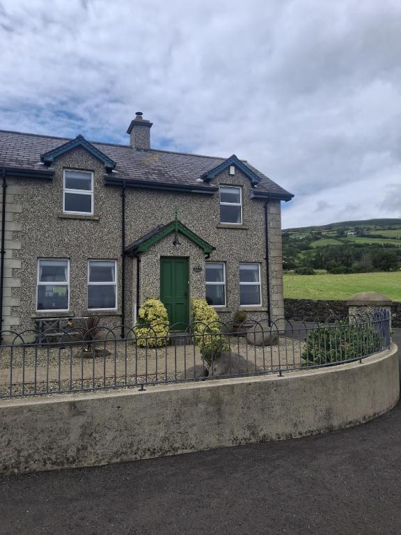 a house with a green door and a fence at Redbrae cottage in Carnlough